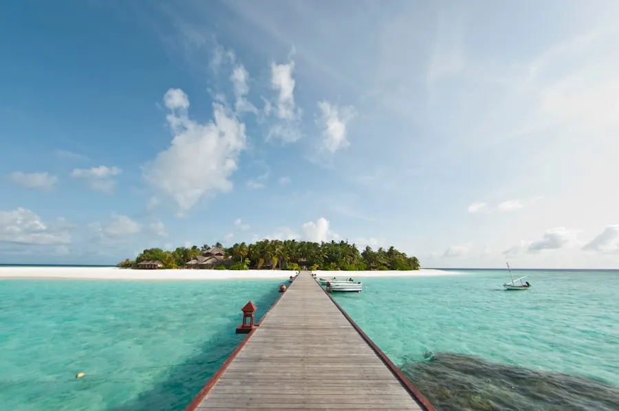 Wooden pier over turquoise water leading toward a tropical island