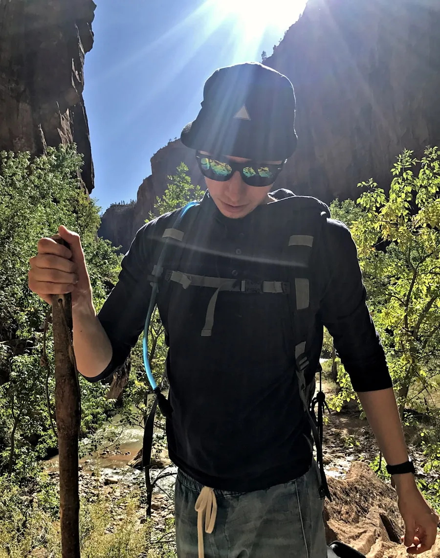 Hand-carved hardwood hiking staff with a shaped grip on a forest trail