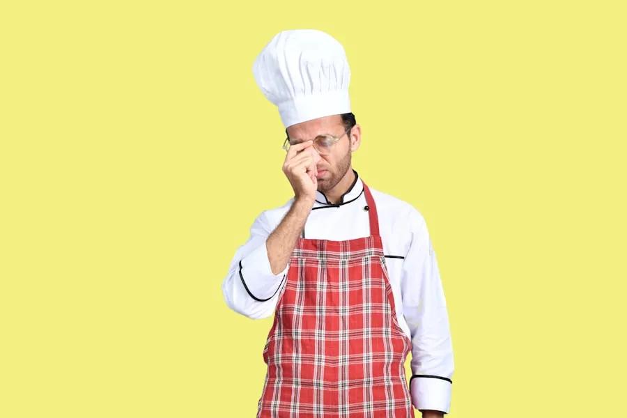 Chef plating an airline chicken breast with sauce drizzled over the top in a restaurant kitchen