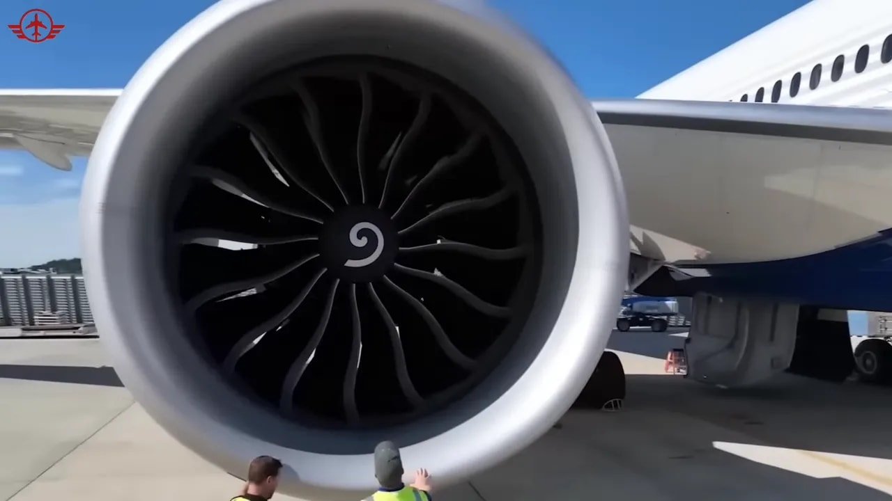 Front view of a GE9X engine installed on a Boeing 777X with ground crew below